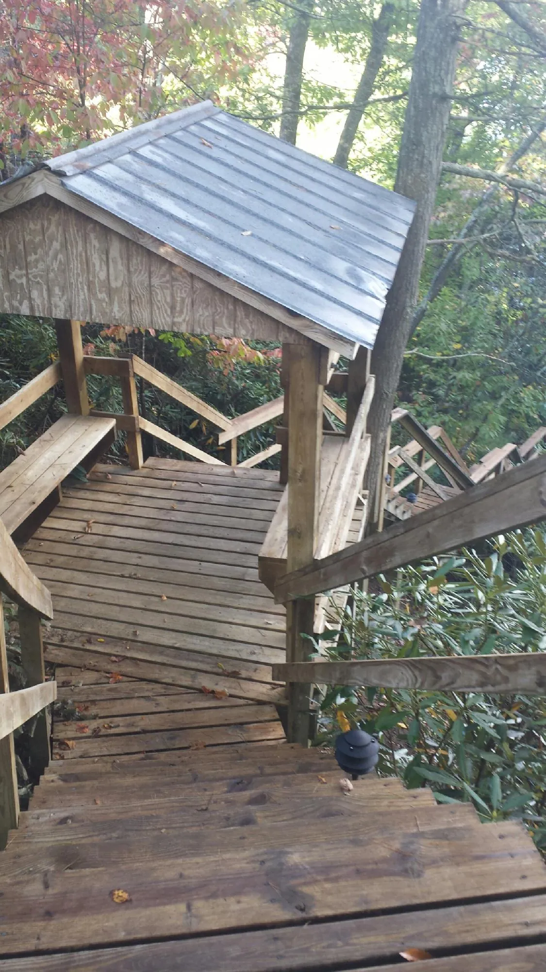 Metal roofed shelter over wooden steps on a wooded walkway — Skylight Repair & Installation work by our crew in Oak Hill